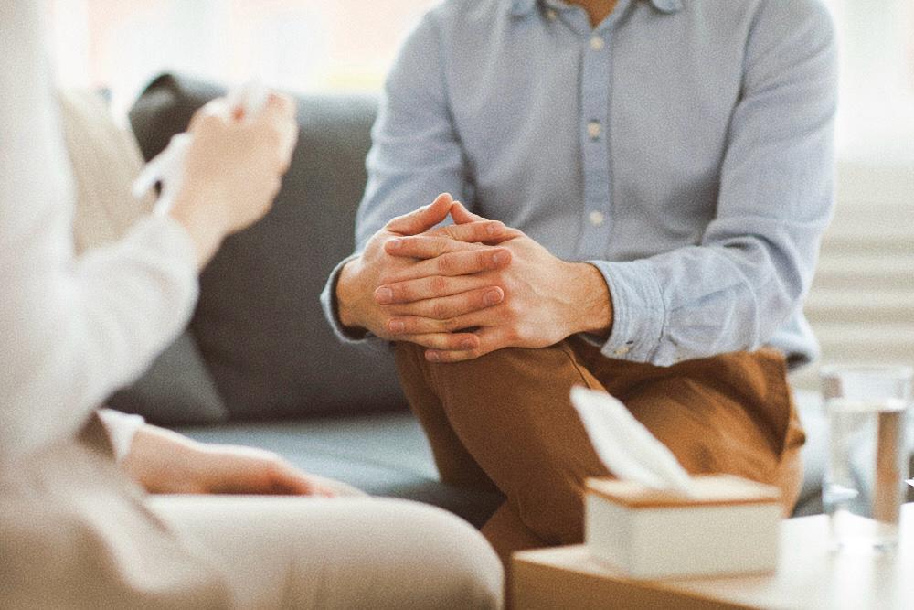 Homem cruzando as mãos sobre a perna